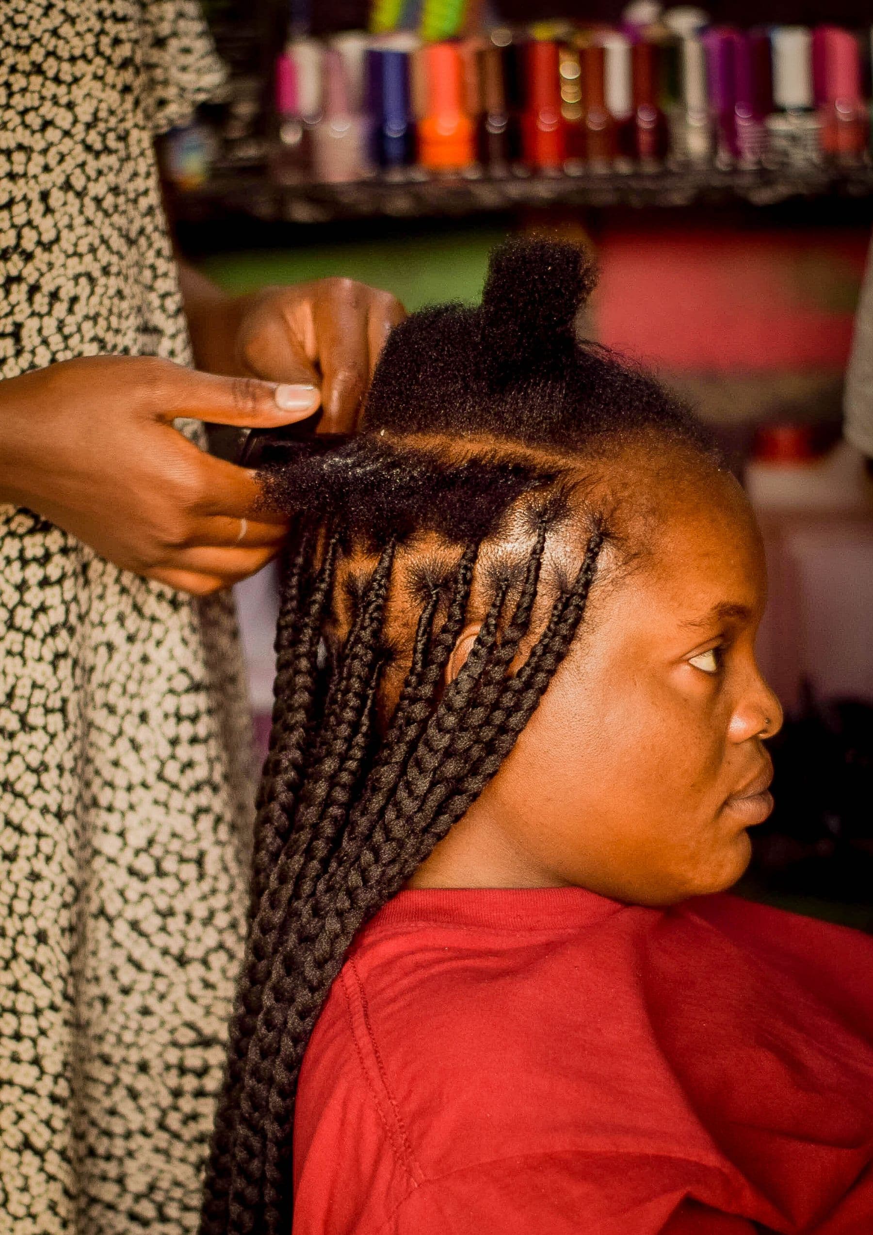 Profissional realizando tranças no cabelo de uma cliente